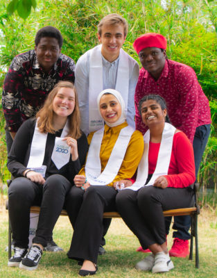 Class of 2020 students from diverse countries and backgrounds seated on a bench smiling