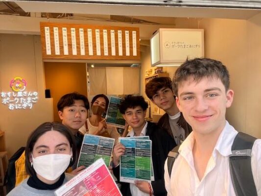 UWC ISAK Japan Grade 11 students with a restaurant owner in Tokyo holding their bilingual menus